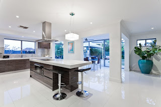 Modern open-concept kitchen with a dark wood island, white counters, and stainless appliances.